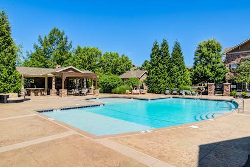 A large outdoor swimming pool surrounded by trees and a pavilion at Sovereign at Overland Park Apartments, Overland Park, KS