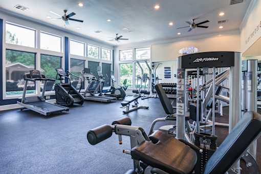 A gym with a variety of equipment including treadmills, weights, and a rowing machine at Sovereign at Overland Park Apartments, Kansas