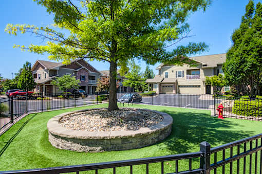 A tree in a circle of rocks is in the foreground of a residential area at Sovereign at Overland Park Apartments, Overland Park, KS