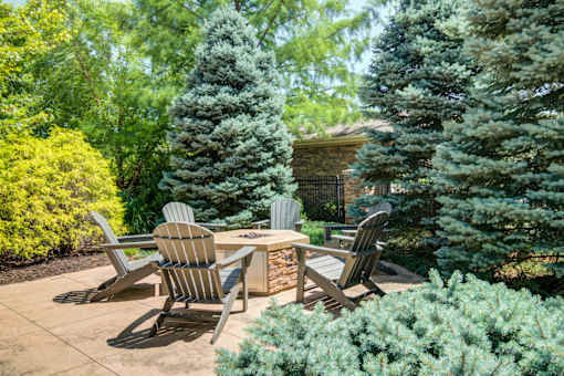A patio with chairs and a table surrounded by greenery at Sovereign at Overland Park Apartments, Kansas, 66213