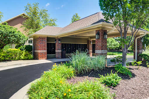 A house with a red brick chimney and a brown roof with a landscaped front yard at Sovereign at Overland Park Apartments, Overland Park, KS 66213