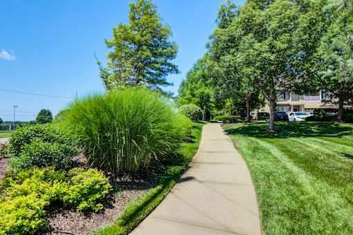 A walkway in a park with green grass and trees at Sovereign at Overland Park Apartments, Overland Park, KS 66213