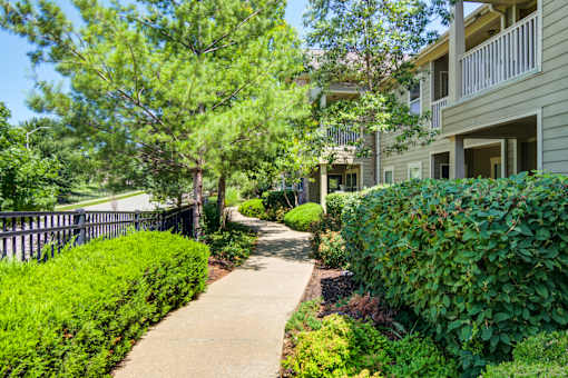 A walkway leads through a landscaped area between two apartment buildings at Sovereign at Overland Park Apartments, Overland Park