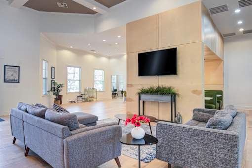 A living room with a grey couch, a black table, and a flat screen TV mounted on the wall at Sovereign at Overland Park Apartments, Kansas, 66213