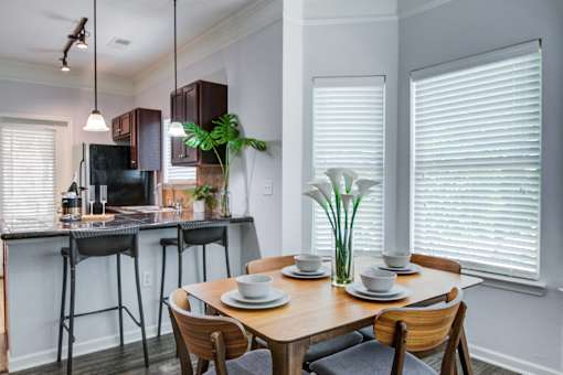 A dining room with a table set for two and a kitchen area with a microwave and oven at Sovereign at Overland Park Apartments, Overland Park, KS 66213