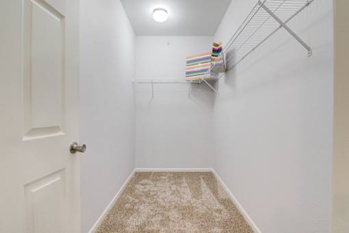 Spacious walk-in closet with built-in shelving and carpet flooring at Sovereign at Overland Park Apartments, Overland Park Kansas