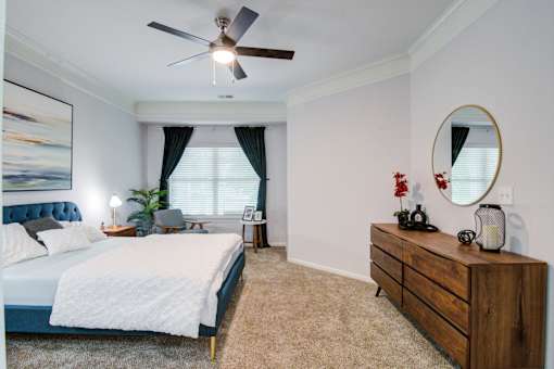 A bedroom with a bed, dresser, and a ceiling fan at Sovereign at Overland Park Apartments, Overland Park Kansas