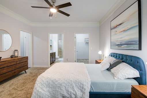 A bedroom with a blue headboard and a ceiling fan at Sovereign at Overland Park Apartments, Overland Park, KS 66213