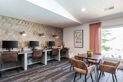 A room with a desk, chairs, and a patterned wallpaper.