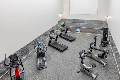 A gym with a variety of exercise equipment including stationary bikes and rowing machines.