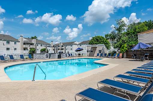 A large swimming pool surrounded by sun loungers and umbrellas.