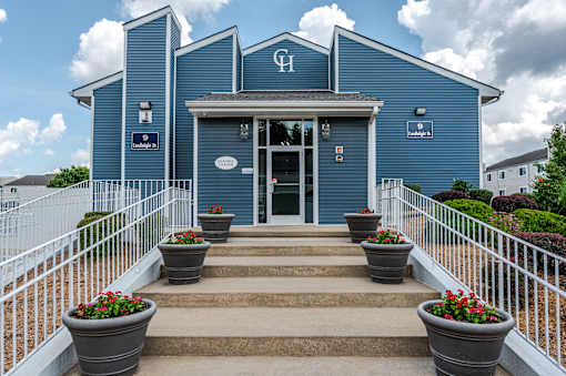 A blue building with a white fence and flower pots in front.