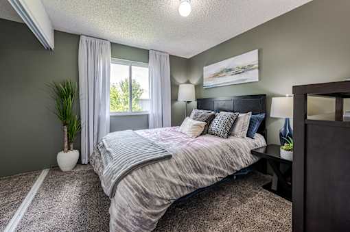 A bedroom with a bed, nightstand, and a painting on the wall.