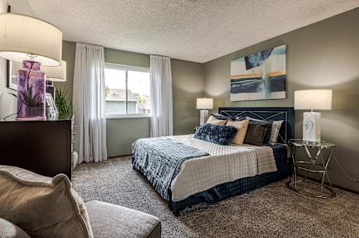 A bedroom with a large bed and a chair.
