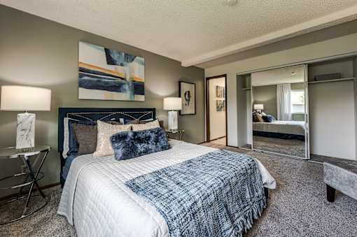 A bedroom with a large bed and a mirror.
