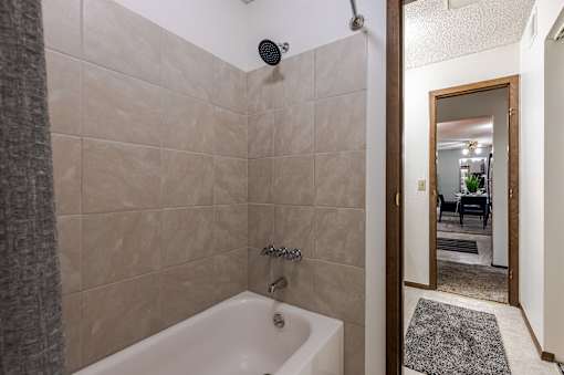 A bathroom with a tiled shower and a white bathtub.