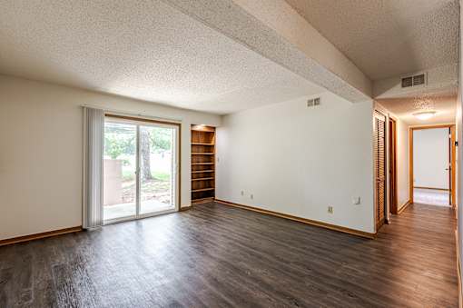 A room with a sliding glass door and a wooden floor.