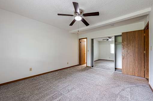 A room with a ceiling fan and carpeted floor.
