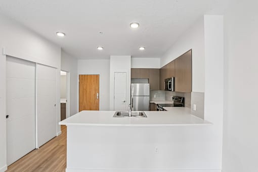 A modern kitchen with white countertops and wooden accents.