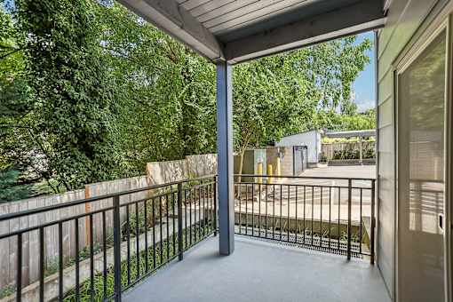 A balcony with a black railing and a view of a backyard.