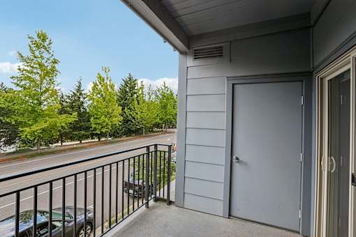 A balcony with a black railing and a grey door.