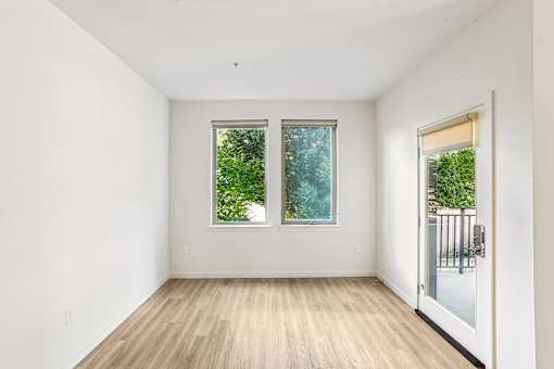 A room with wooden floors and two windows.