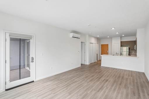A spacious room with a sliding glass door and wood flooring.