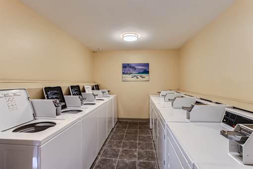 A laundromat with washers and dryers lined up.