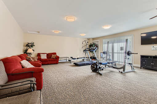 A living room with a red couch, a blue exercise bike, and a TV.