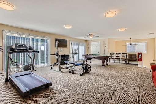 A spacious room with a treadmill, exercise bike, and a table set up for dining.
