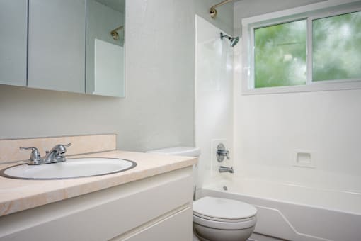 A white bathroom with a toilet, sink, and bathtub.