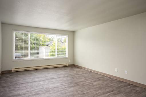 A room with a window and wooden flooring.