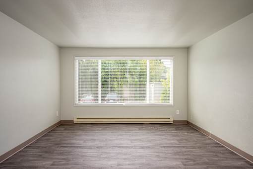 A room with a window and a wooden floor.