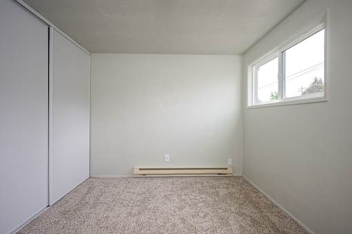 A room with a carpeted floor and a window.