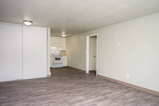 A kitchen with white cabinets and a white oven is visible through a doorway.