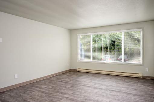 A room with a window and a wooden floor.