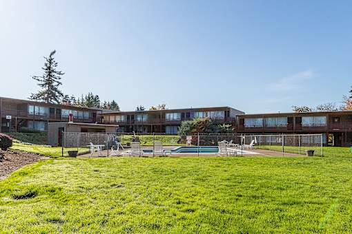 A large grassy area in front of a building with a pool table and chairs.