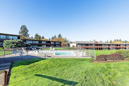 A large grassy area in front of a building with a pool.