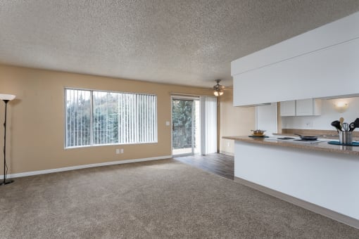 an empty living room with a kitchen and a door to a patio