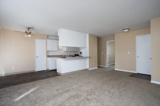 an empty living room and kitchen with a ceiling fan