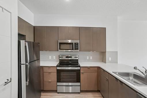 A modern kitchen with a stainless steel refrigerator and oven.