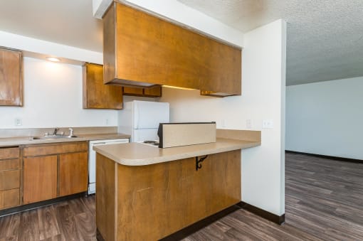 Pinewood Terrace Apartments | View of kitchen from dining room. Maple colored cabinetry with counter space for stools.