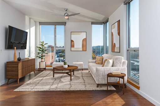 A living room with a white couch, a wooden coffee table, and a flat screen TV mounted on the wall.