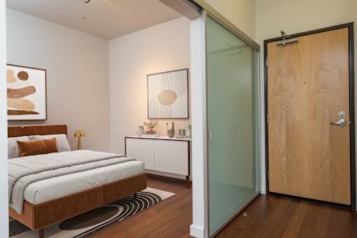 A bedroom with a bed, nightstand, and artwork.