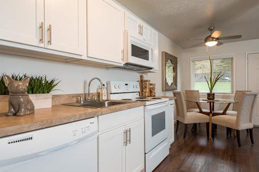 A kitchen with white appliances and wooden floors.