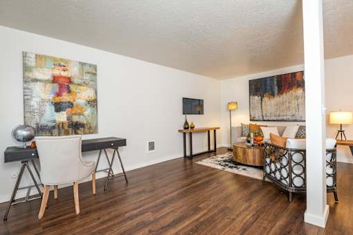 A living room with a white chair and a painting on the wall.