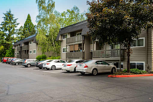 A parking lot with cars and apartment buildings in the background.