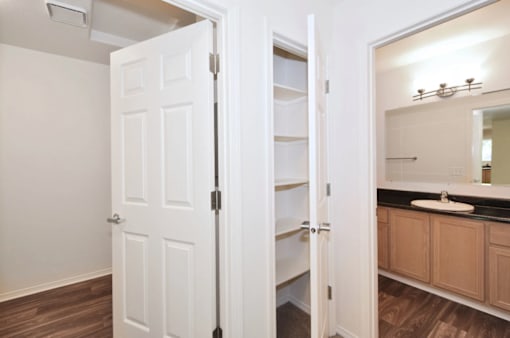 A white door is open to a bathroom with a sink and mirror.
