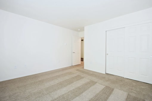 A room with a striped carpet and two white doors.
