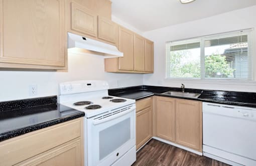 A kitchen with wooden cabinets and black countertops.